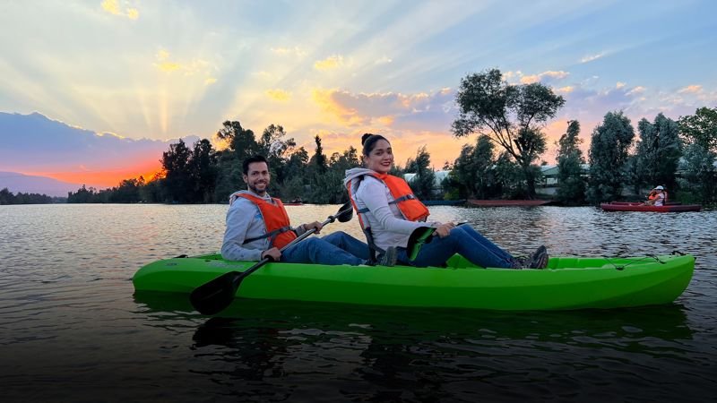 Kayakista en kayak verde con rayos del sol naciente sobre los canales de Xochimilco